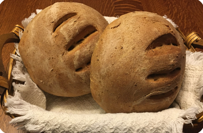 Two round loaves of rye bread in a small basket