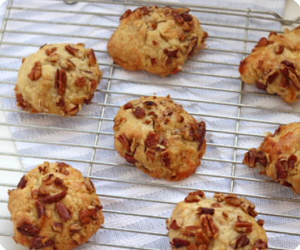 Seven cookies covered in pecans sitting on a wire rack