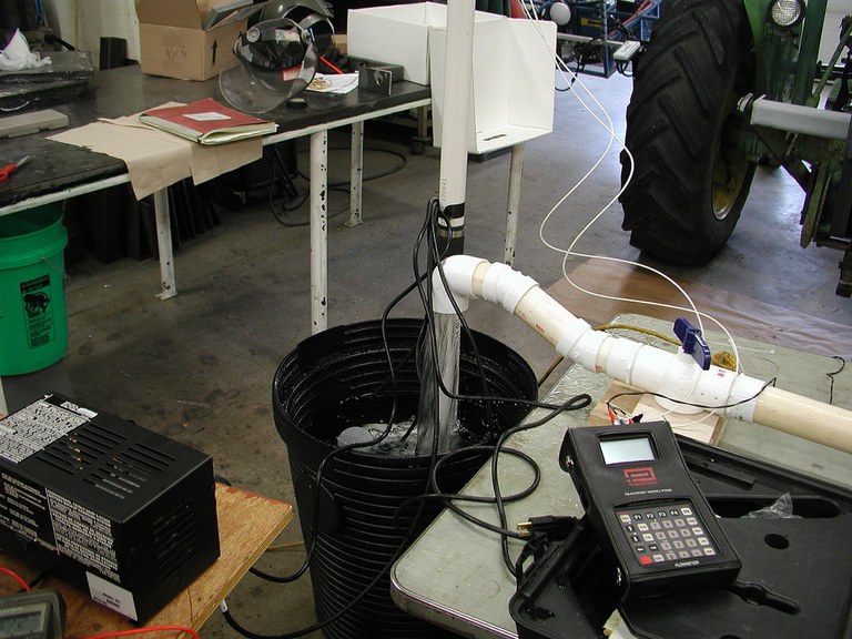 Figure 8. Backup pump test stand with water flowing into a sump containing two pumps. The charger is on the lower left, and the ultrasonic flow meter is on the right.