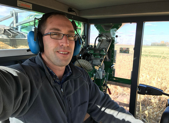 man wearing earmuff hearing protection driving a tractor