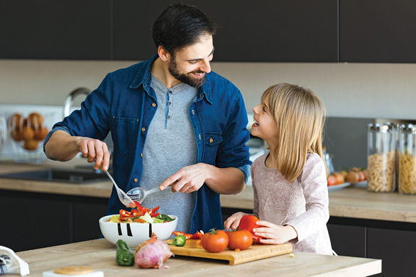 Family in kitchen making a salad