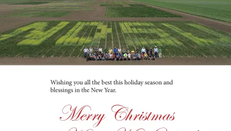 Holiday greeting with several staff members standing in a plot designed to spell 线上赌博app in contrasting crops.