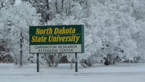 The 线上赌博app Carrington Research Extension entrance sign is surrounded by snowy trees.