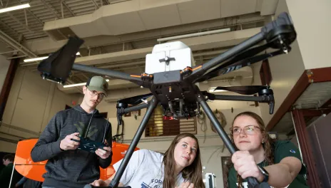 three students working with a drone