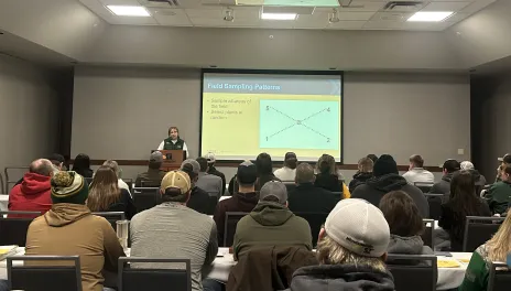 Jan Knodel stands at the front of a lecture hall describing a sweep path for collecting insects.