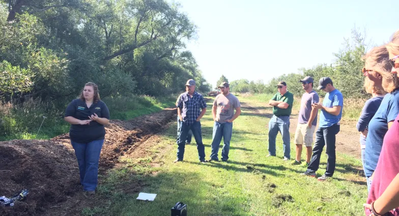 woman standing next to manure compost pile talking to a crowdabout