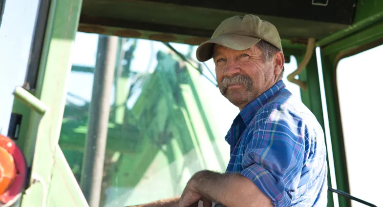 a man in a tractor looking back at the camera with a smile