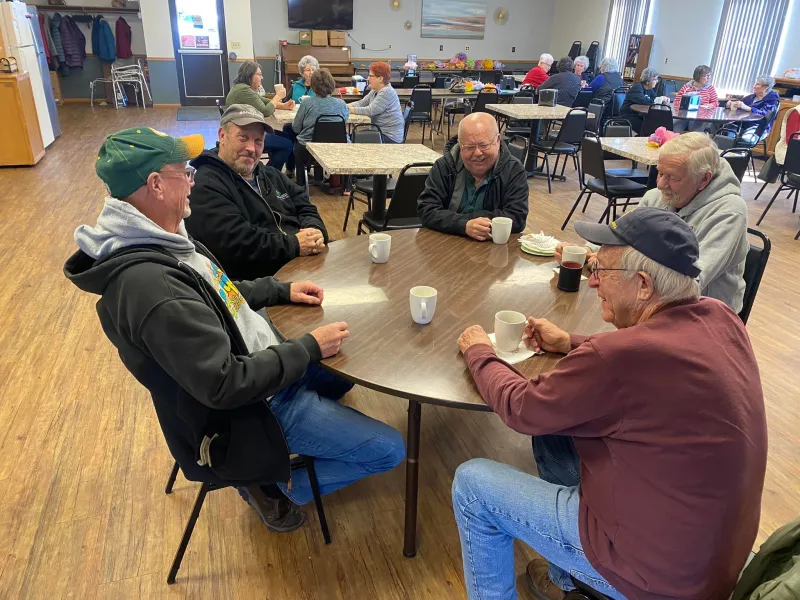 elderly men visiting around a round table