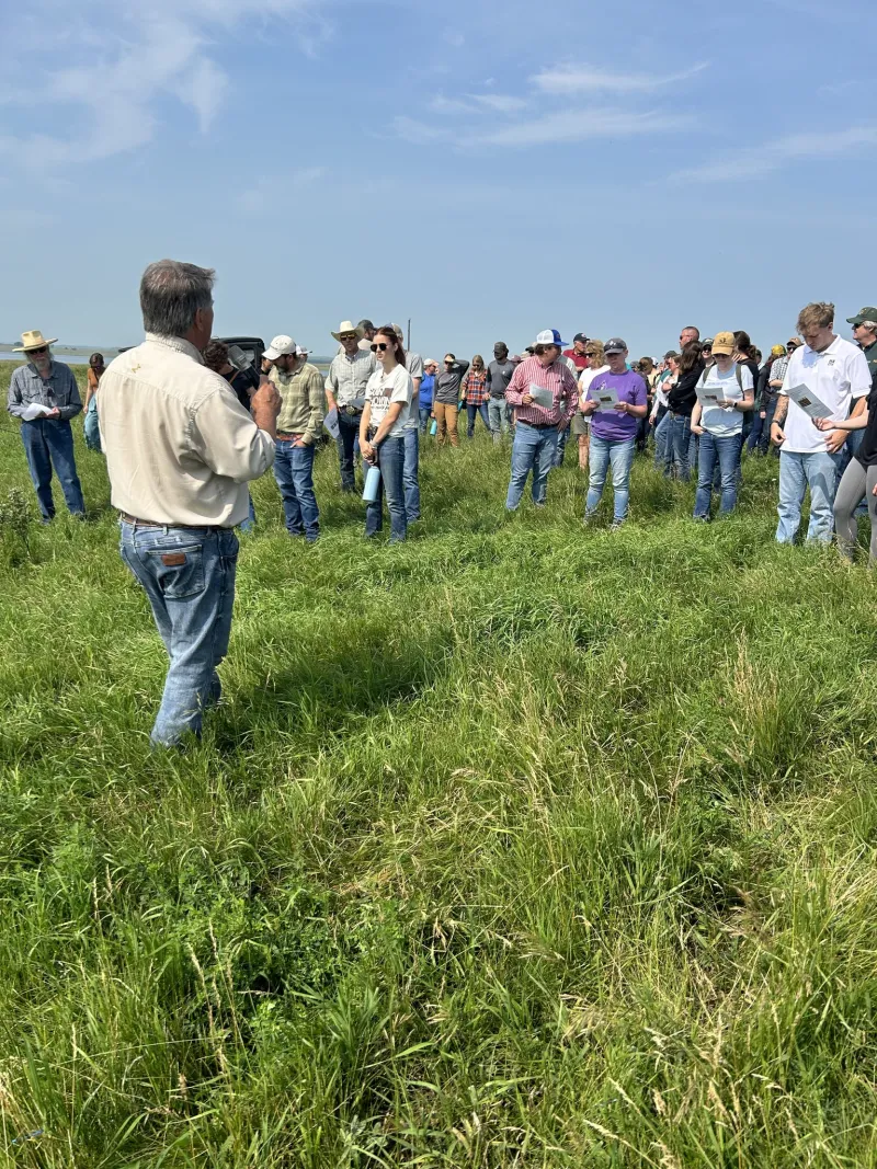Man speaking to a crowd in a field 