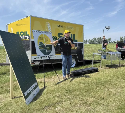 A man does a presentation on Soil Health principles in a farm field