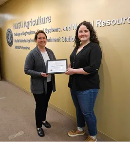 Woman presents an award certificate to another award