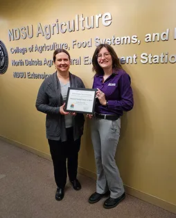 woman presents an award to another woman