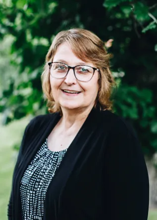 A woman with glasses smiles
