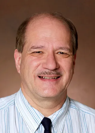 Gregory Oswald smiling confidently at the camera