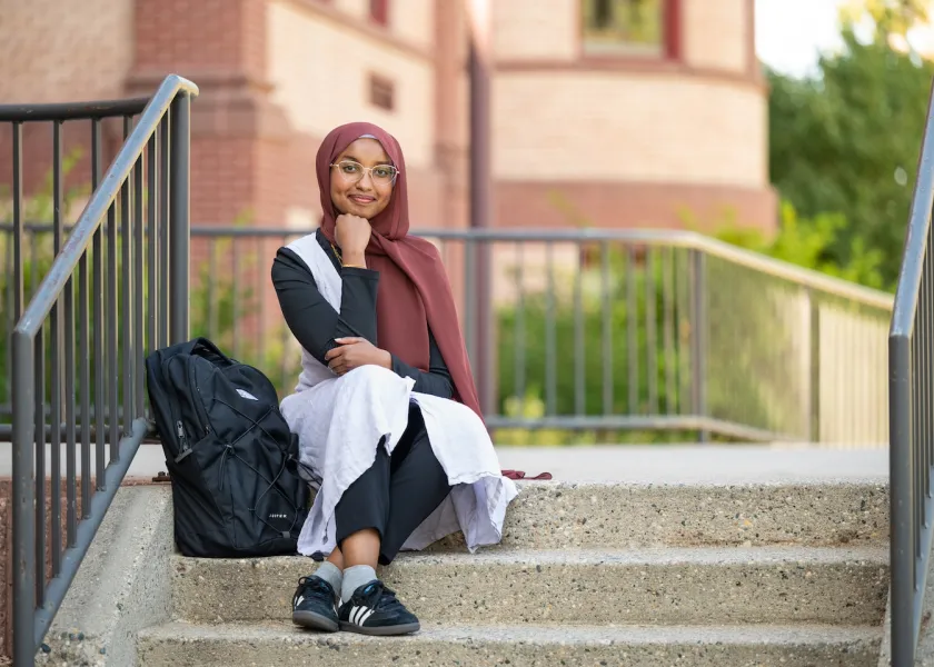 First generation student sitting on campus stairs