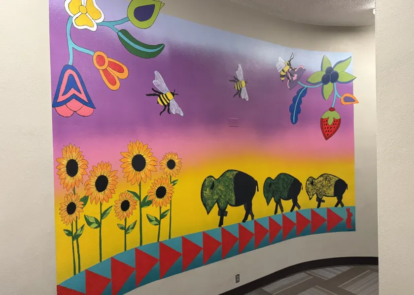 Mural featuring bison, a colorful sunrise, bees and sunflowers.