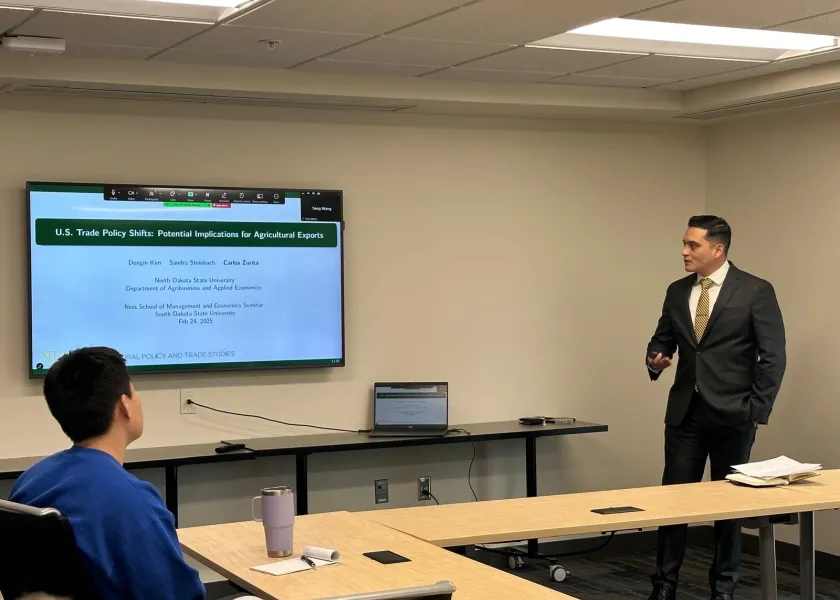 Carlos Zurita, senior research economist with 线上赌博app’s Center for Agricultural Policy and Trade Studies, stands at the front of a room giving a presentation.
