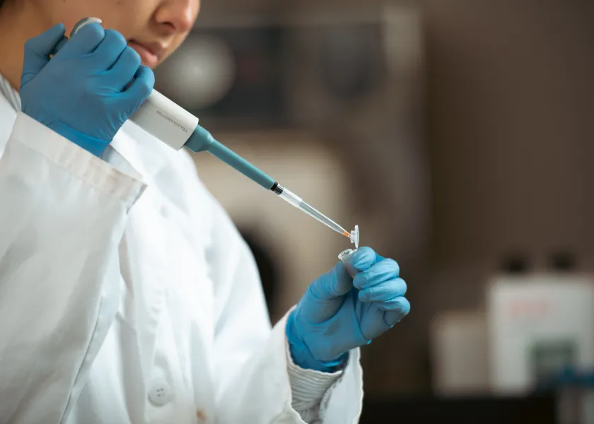 student filling a testing container in a lab