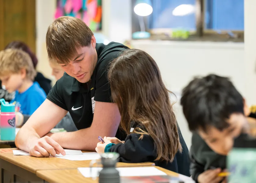 student helping children in the classroom