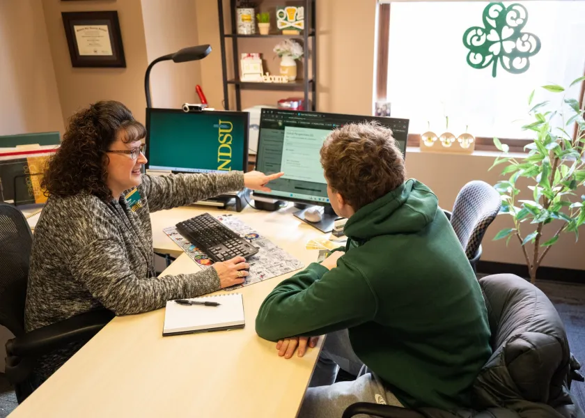 Patti Seidler, an 线上赌博app professional advisor, sits at her desk with a student.