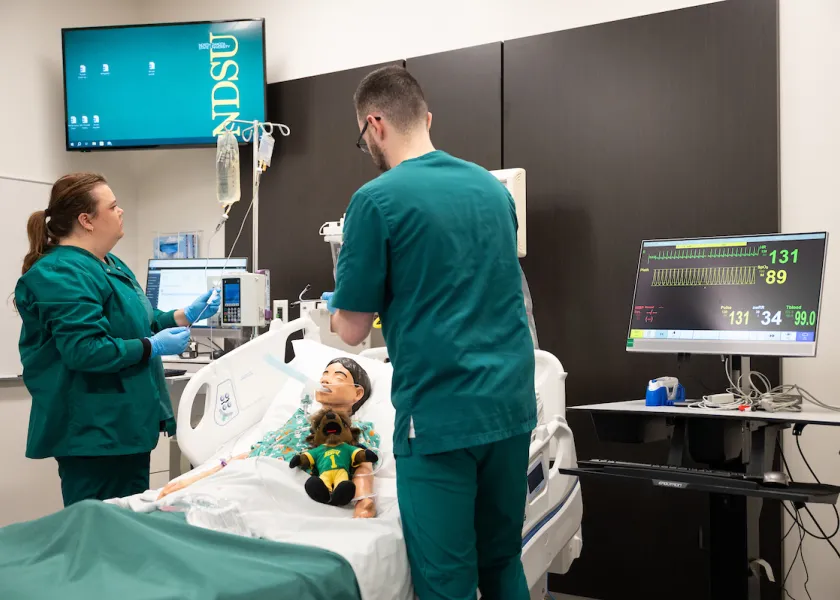 students practicing nursing techniques on a test dummy