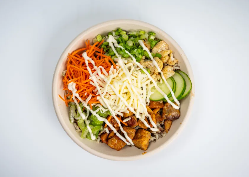 buffalo chicken grain bowl with chicken, cheese, carrots, celery, cucumbers, and grains
