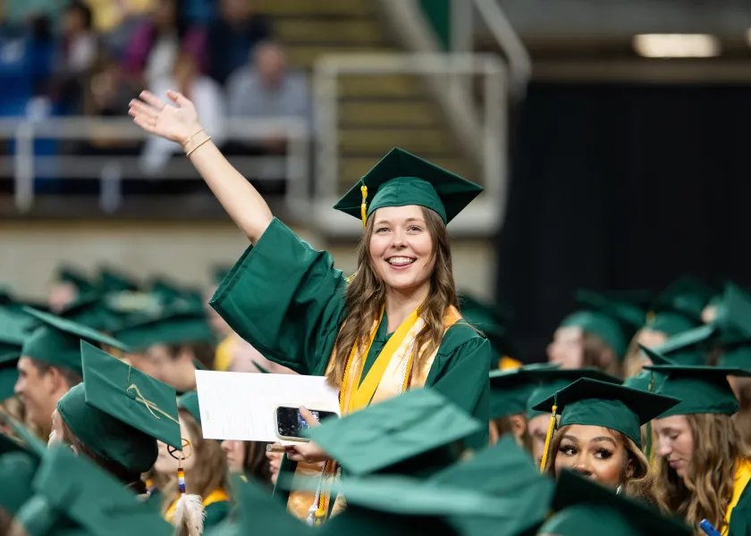 A graduating 线上赌博app student waves at the crowd during the spring commencement ceremony in the Fargodome.