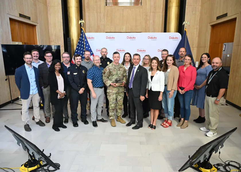 A group of people smile while holding an award