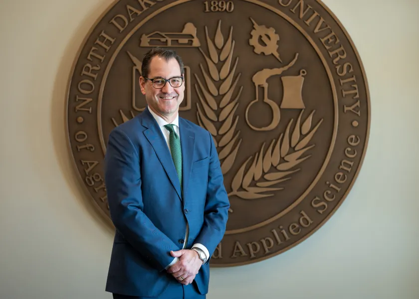 President Cook in front of the President's Seal in Old Main