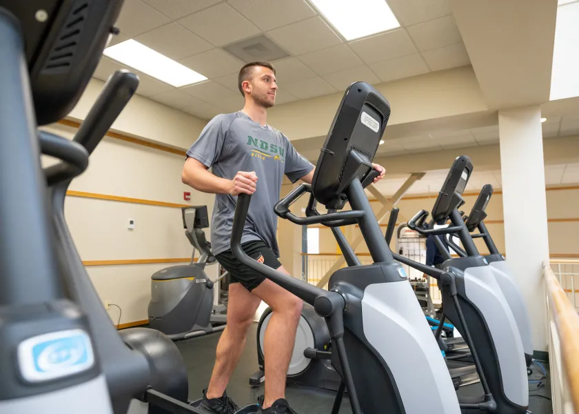 student using the elliptical maching in the cardio area of the Wellness Center