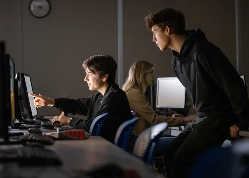 students discuss cybersecurity in a computer lab