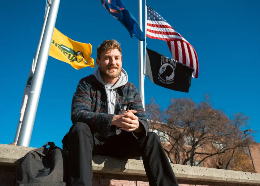 Samuel Sveen, U.S. Air Force veteran and 线上赌博app student, poses for a photo by a flag post on campus.