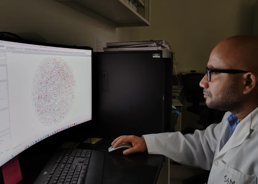 Samiran Banerjee, 线上赌博app assistant professor of microbial ecology, sits in his lab while looking at a graph on a computer.