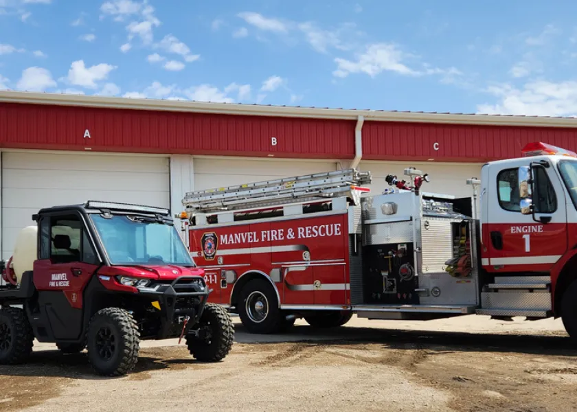 A fire truck and a UTV are parked outside of a fire department