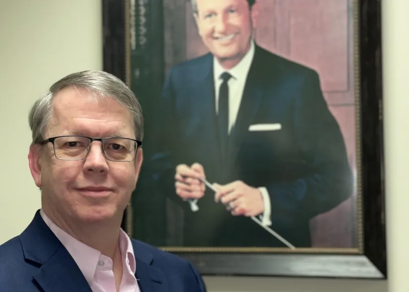 Lance Richey stands in front of a painting of Lawrence Welk.