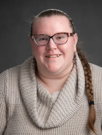 Hall director, Rachael, posing for the camera with a cream color sweater on and hair in a braid.