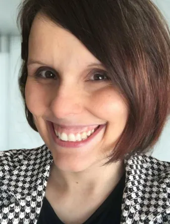 Melissa Vosen Callens looking at the camera, smiling, wearing a houndstooth blazer