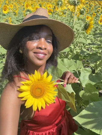 Christiana in a field of sunflowers holding a single flower.