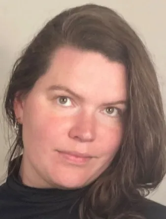 A headshot of RoseE Hadden a white woman with brown hair in her mid-30s.