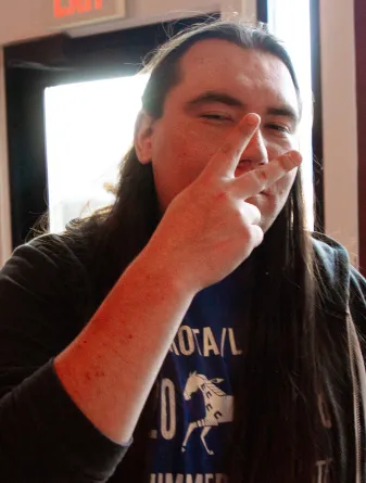 Tyrel looking at the camera hold the peace sign in front of his face.