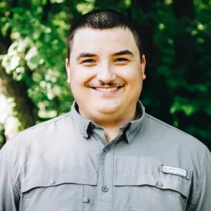 A Man smiling with trees in the background