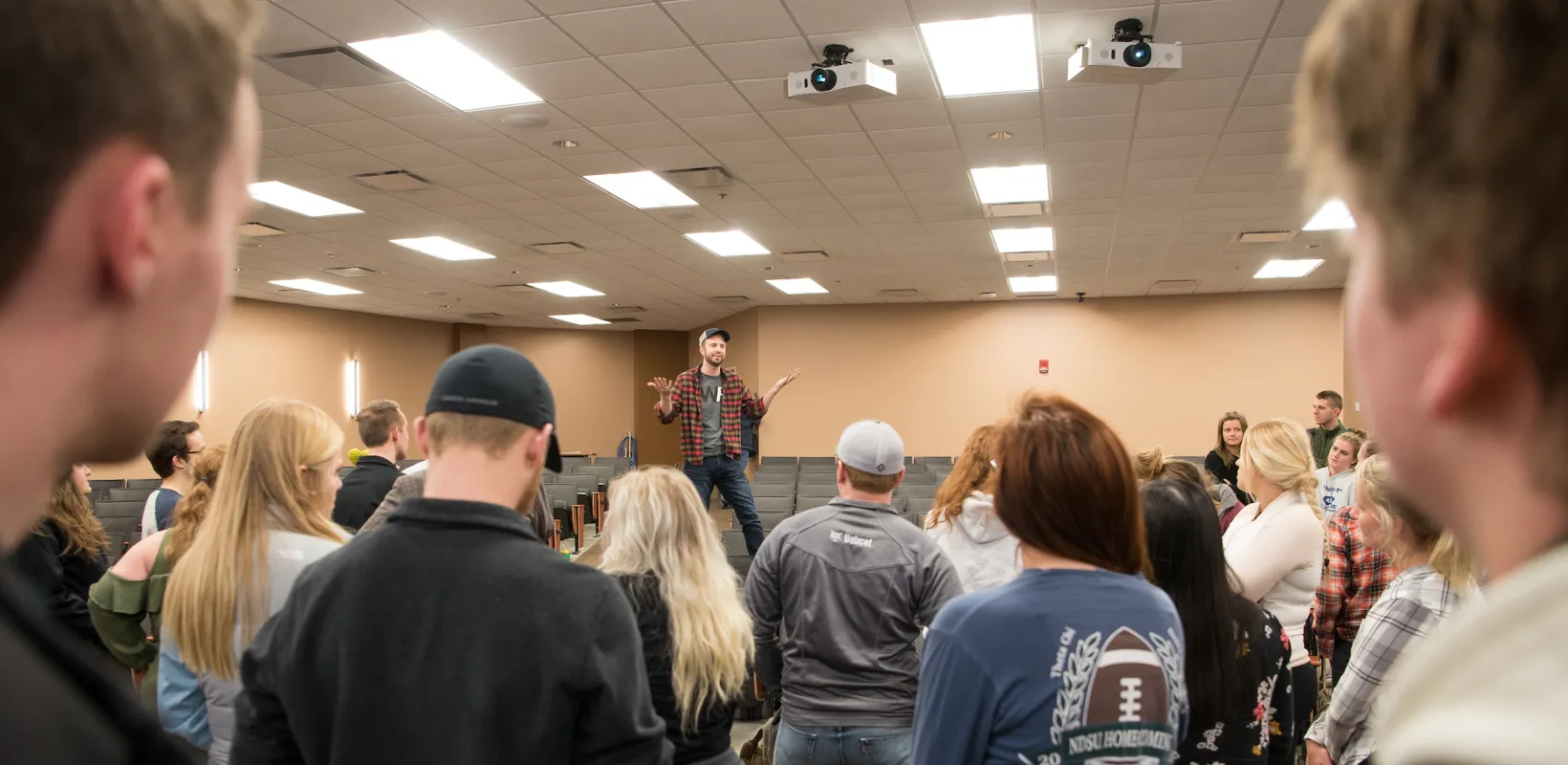 man speaking to a large group of people in a classroom