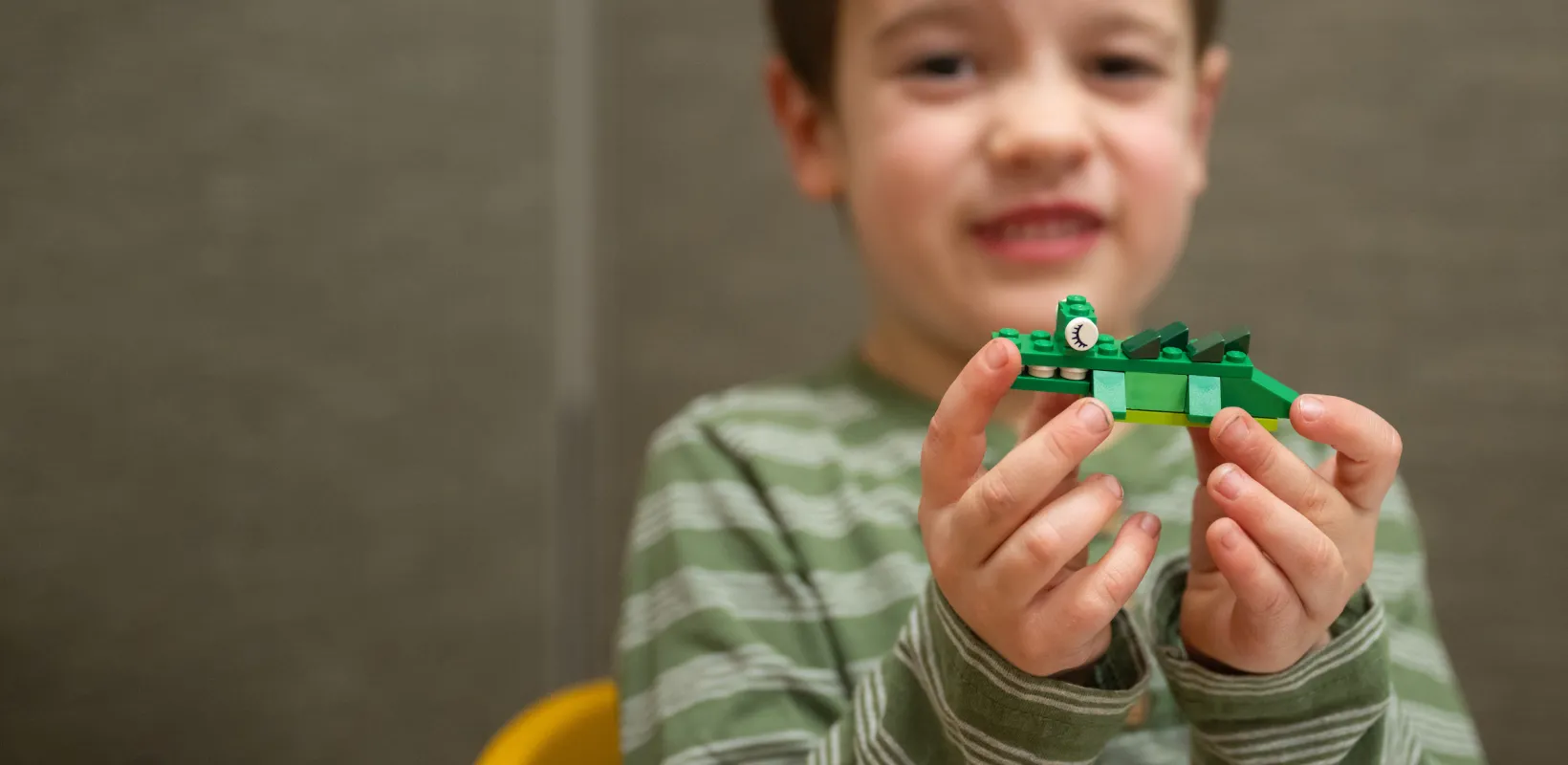 child holding up a Lego creation