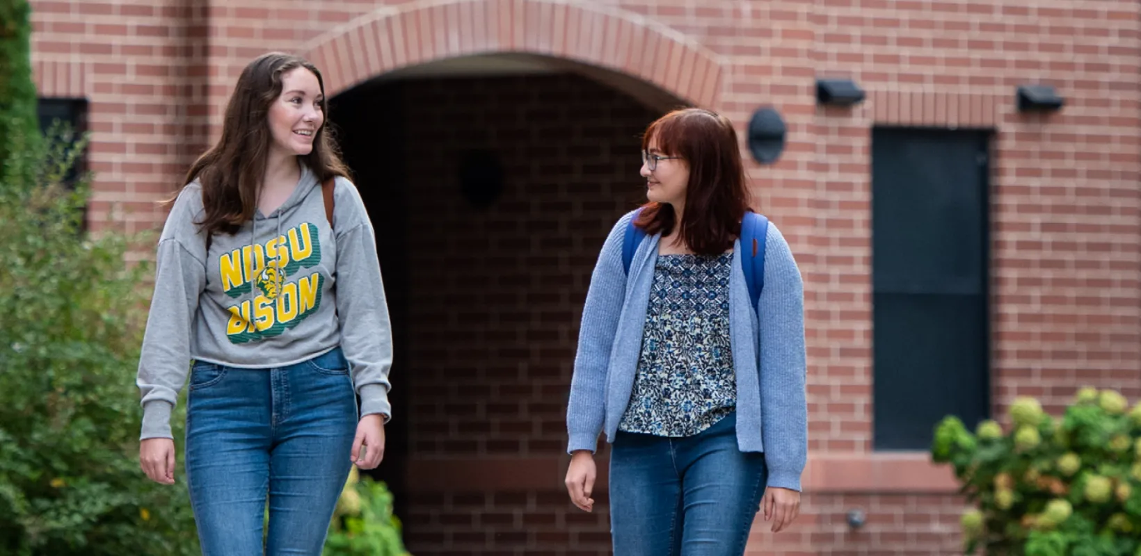 Two students walking out of Bison Court Apartments