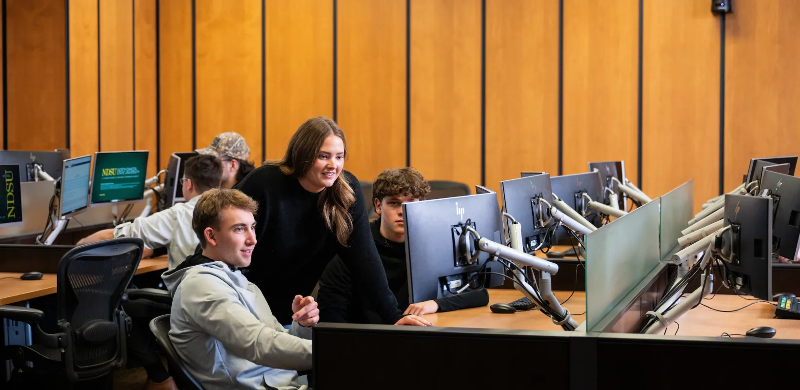business students gathered around a computer in the trading room