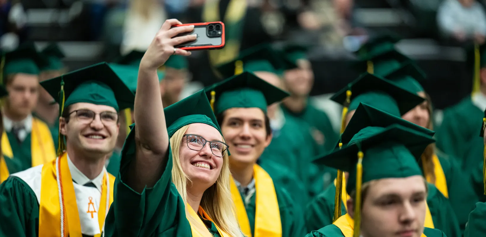 线上赌博app graduates taking group selfies at commencement celebration