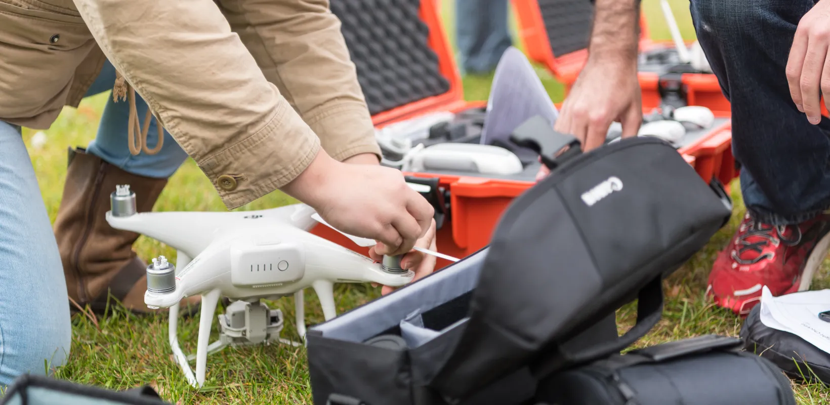 Students working with drone equipment in grassy field. 