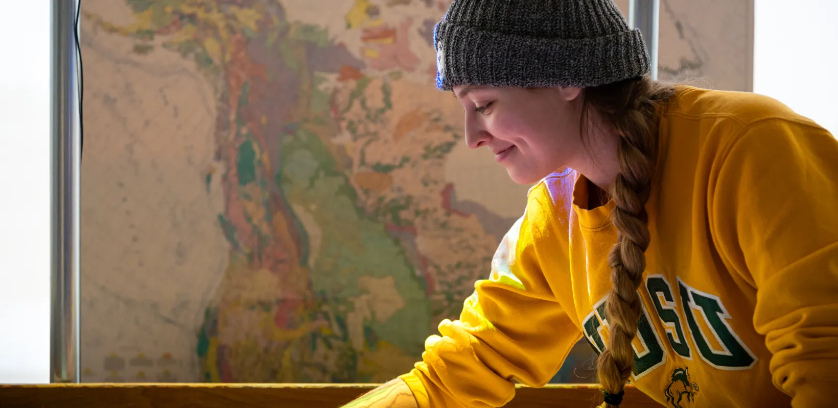 Student wearing a yellow 线上赌博app sweatshirt working in AR sandbox.