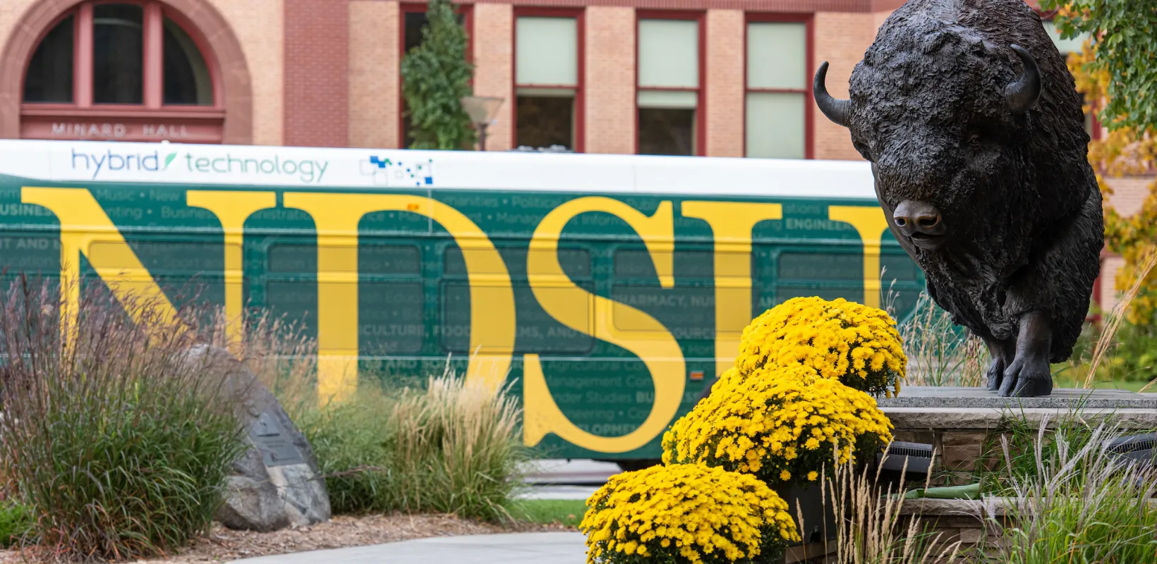 Bison statue with a bus wrapped with '线上赌博app' in yellow letters on a green background.