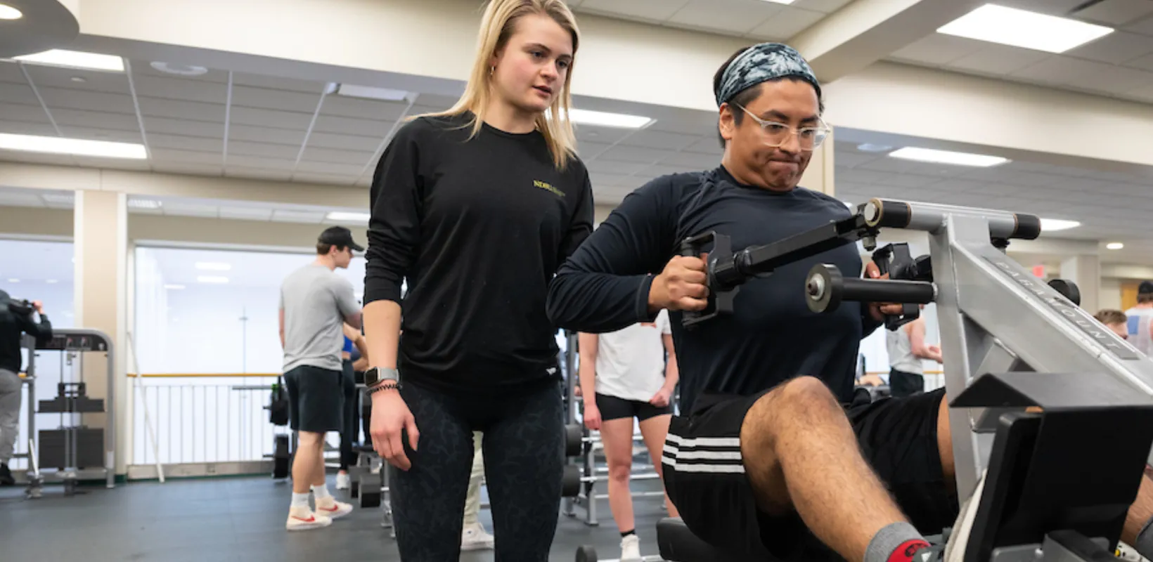 Female personal trainer instructing male client on weight lifting